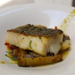 Bacalao asado con cama de verduras salteadas, cilantro y lima