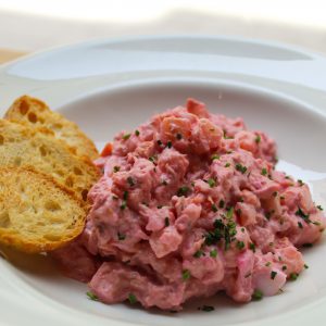 Ensaladilla rusa de patata, zanahoria, atún, huevo y mahonesa de remolacha servido con pan tostado