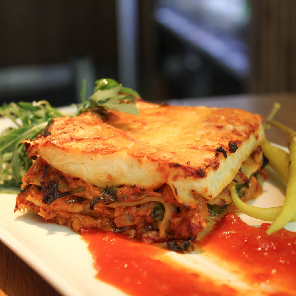 Lasaña de bonito con huevo y piparras con salsa de tomate y brotes verdes