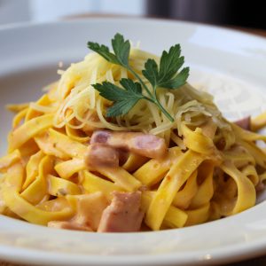 Tagliatelle con panceta ahumada, nata y tomate.