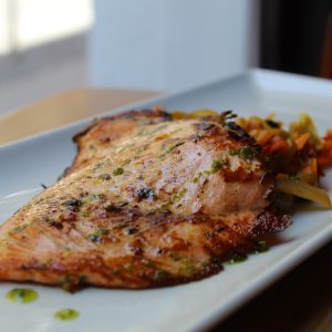 Salmón asado con cilantro y lima, sobre cama de verduras